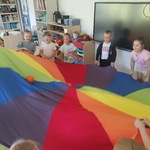Dzieci próbują wrzucić piłkę w środek chusty.