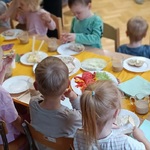 Dzieci siedzą przy stole. Dzielimy się radością.jpg