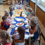 Grupa dzieci siedzi przy stole i je śniadanie. Razem tworzymy naszą grupę.jpg