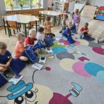 dzieci siedzą na dywanie i oglądają co maja w workach