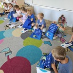 dzieci siedzą na dywanie i zagladają do woreczków