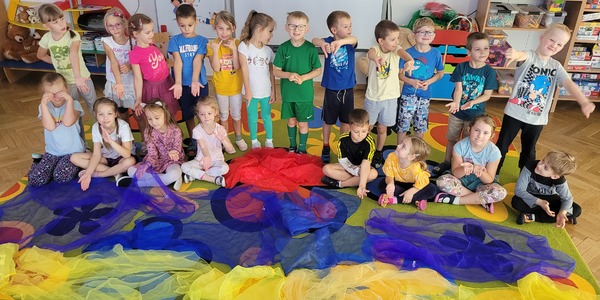 grupa dzieci prezentuje __obraz zachodzącego słońca__ ułożony z kolorowych chust.jpg