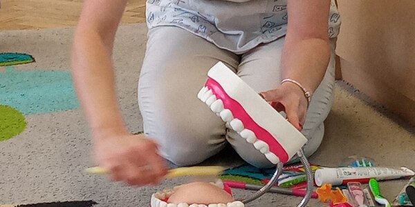 pani stomatolog pokazuje na sztucznej szczęce jak należy czyścić zęby.jpg