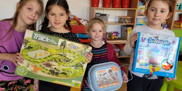 grupa dziewczunek trzyma pudełka z nowymi zabawkami.jpg