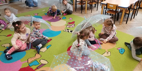Dzieci siedzą pod parasolami.jpg