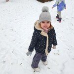 dziewczynka stoi na śniegu, uśmiecha się