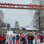 dzieci stoją w rzędzie pod bramą z napisem Wioska św. Mikołaja.jpg