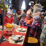 grupa dzieci stoi wokół stołu w jadalni Mikołaja.jpg