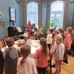 dzieci w sali muzealnej oglądają stare meble i pianino.jpg