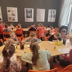 dzieci przy stolikach w pracowni muzealnej wykonują pacę plastyczną.jpg
