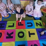 Dzieci siędzą wokół maty z literami.jpg