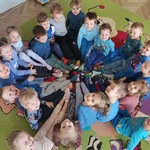Grupa dzieci siedzi na dywanie tworząc koło.jpg
