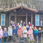 grupa dzieci stoi przed starym drewnianym domem.jpg
